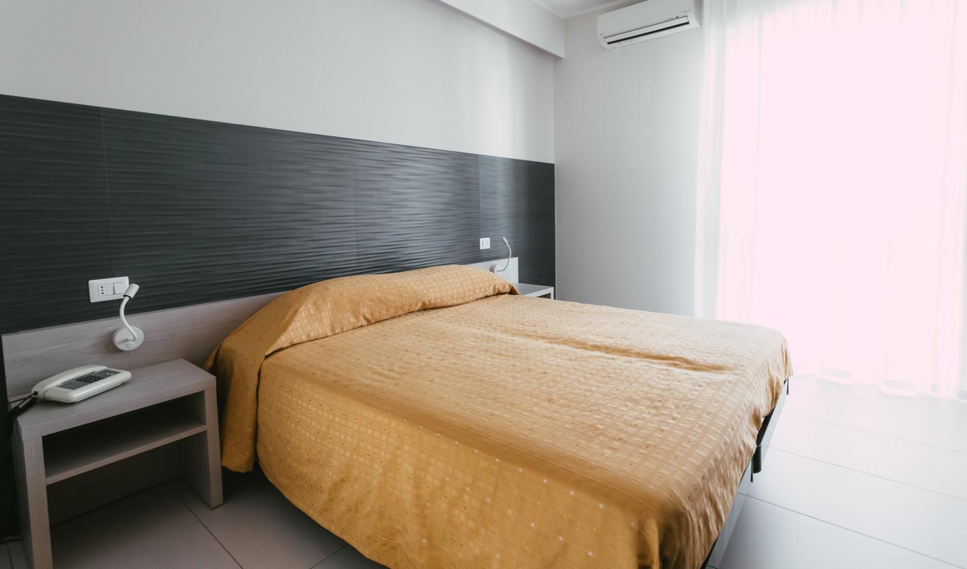 Camera da letto moderna con letto matrimoniale, aria condizionata e luce naturale.