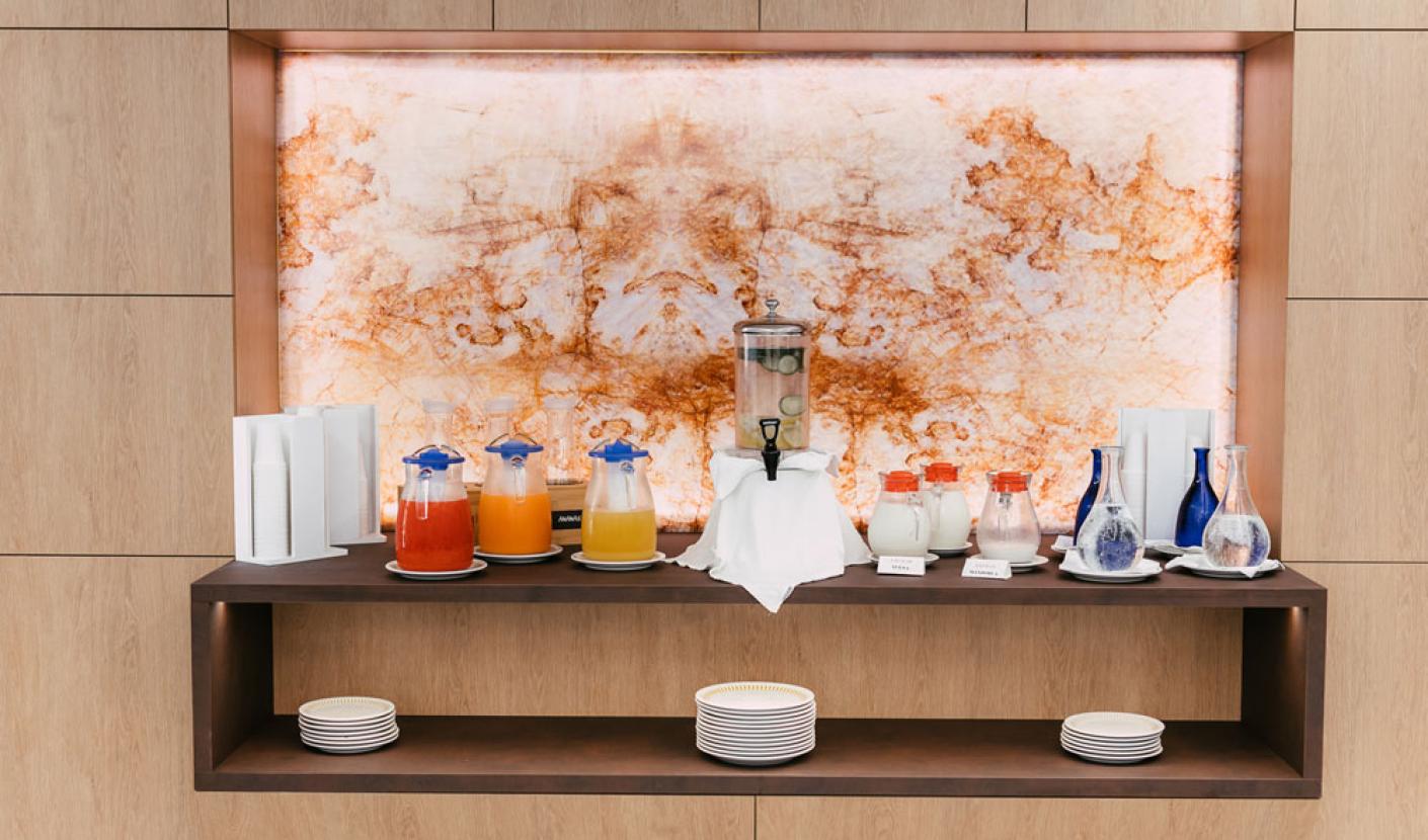 Buffet with fruit juices, milk, and infused water in elegant containers.