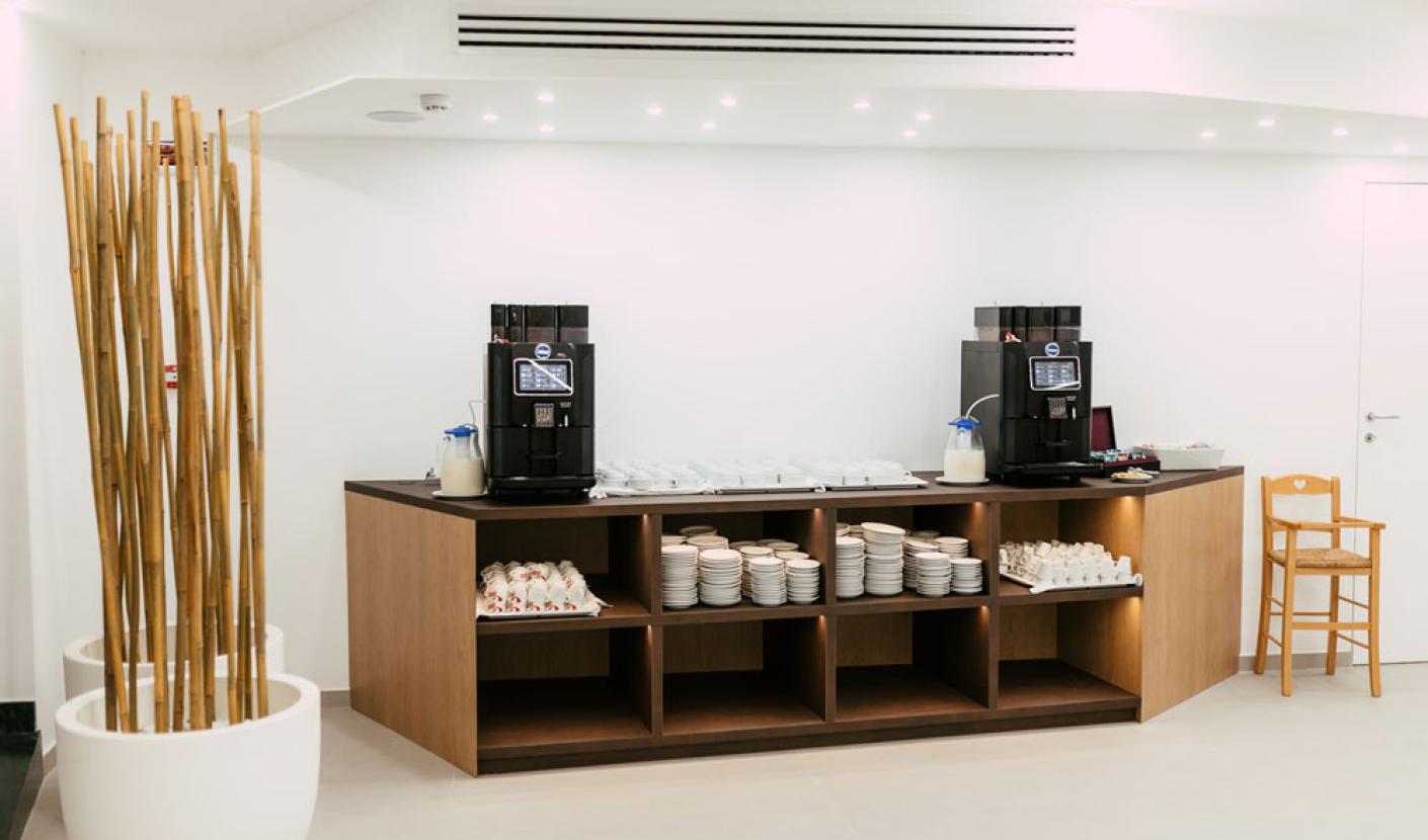 Coffee corner with automatic machines and neatly arranged cups on shelves.
