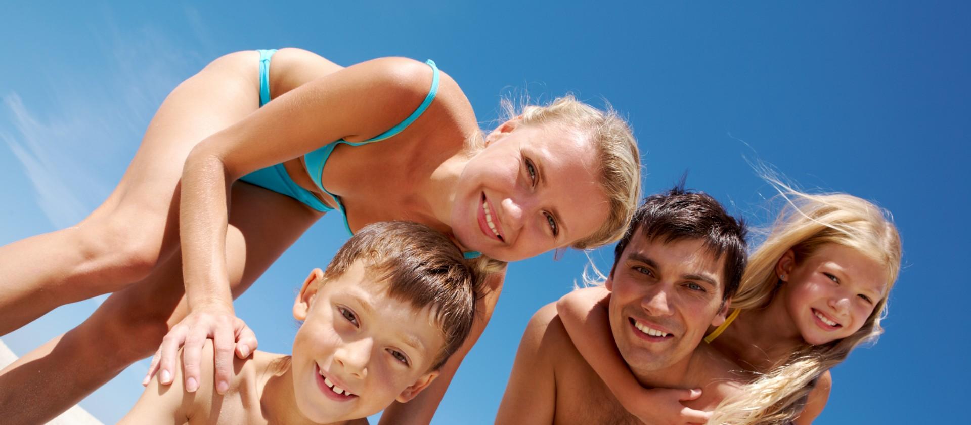 Famiglia felice in spiaggia con cielo azzurro.